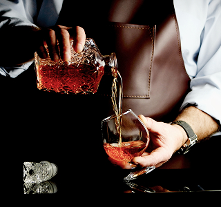 Personne versant du whisky d'une carafe dans un verre
