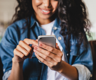 Femme souriante en chemise bleue utilisant son smartphone