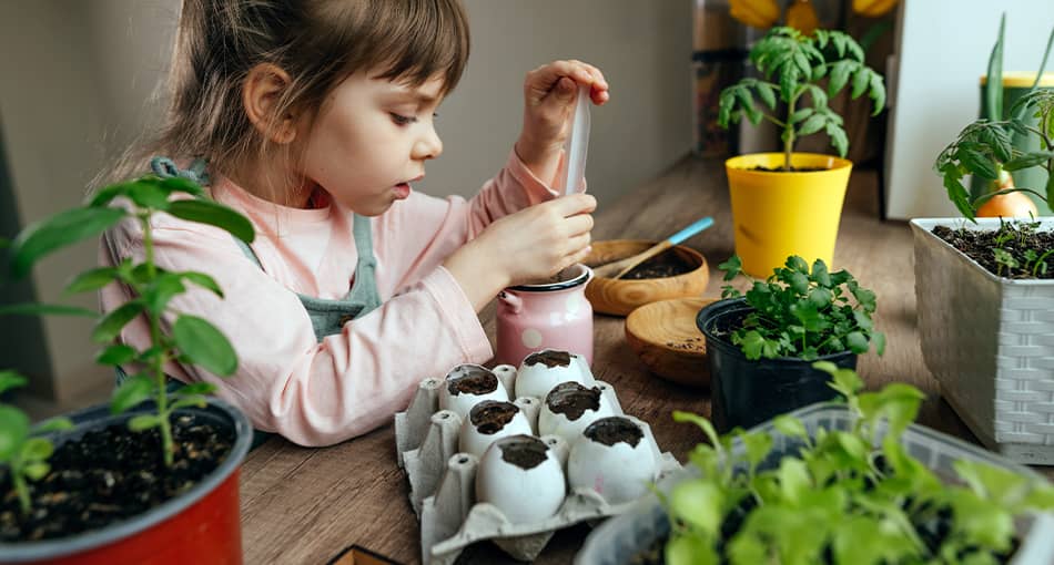 Une petite fille concentrée plantant des graines dans un pot rose